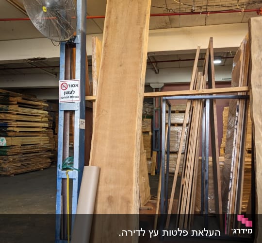 לוחות עץ גדולים מונחים במחסן על מתקן מתכת